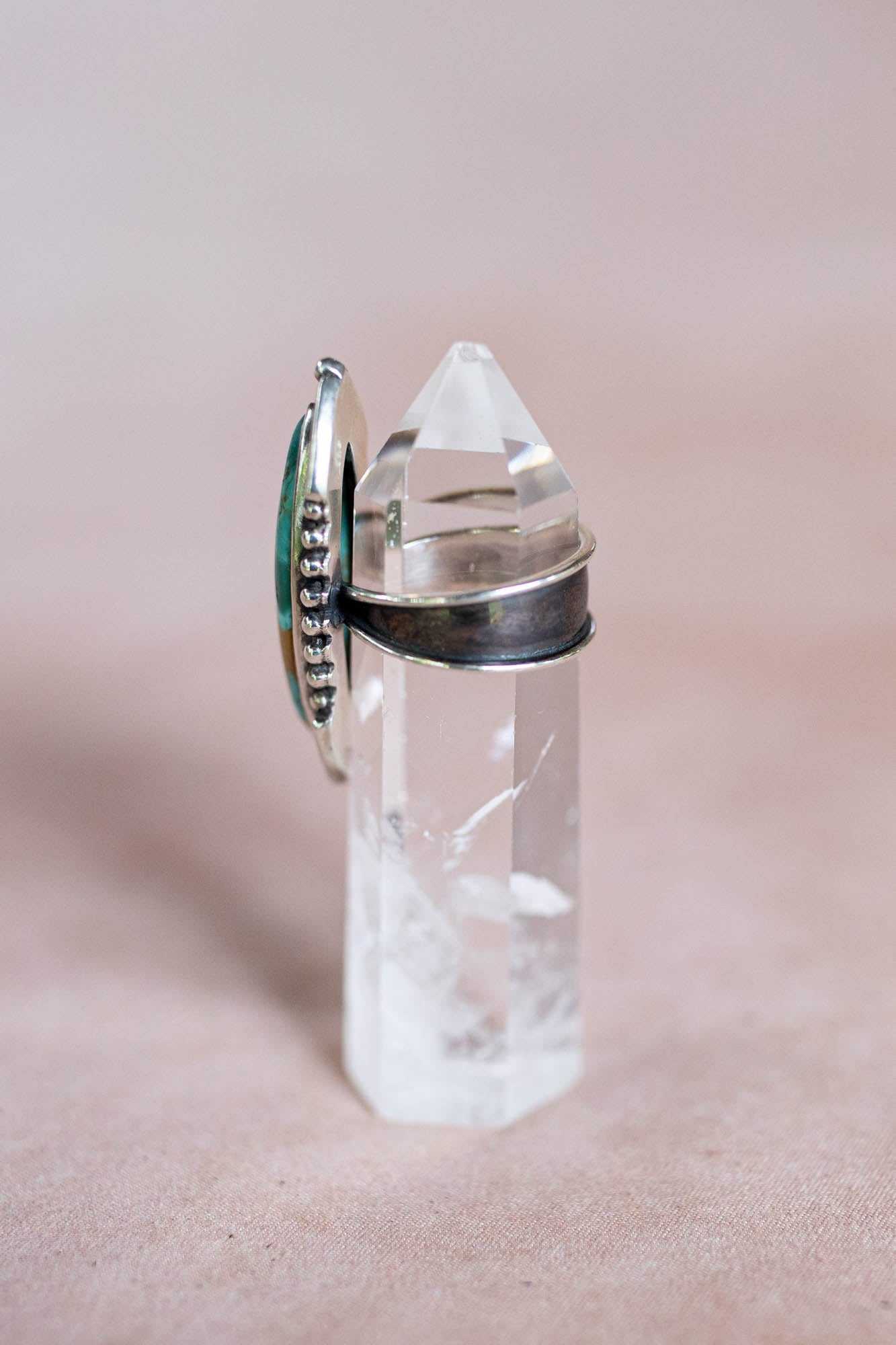 silver and turquoise ring on a crystal stand