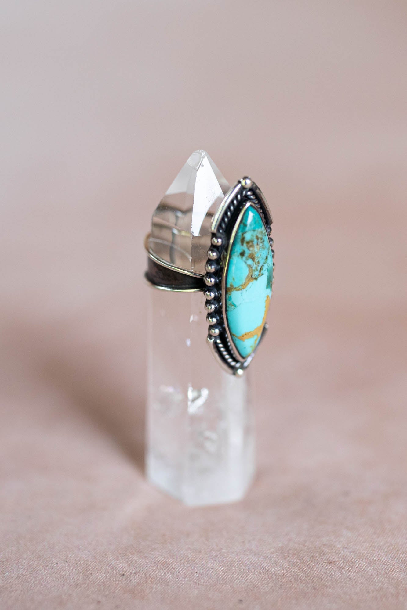 Turquoise ring with silver band on a clear crystal stand 